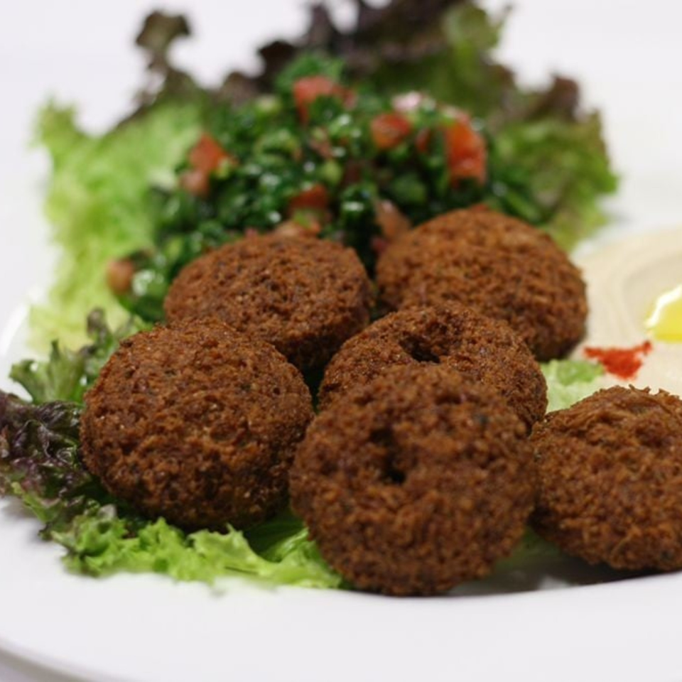 Crispy falafel balls on a bed of fresh lettuce with tabbouleh and hummus.