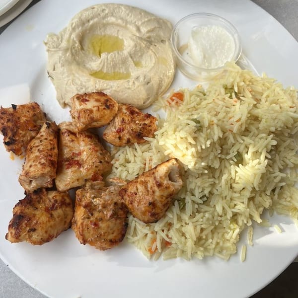 LE Chef Mediterranean chicken shish tawook with rice, hummus, and garlic sauce on a white plate.