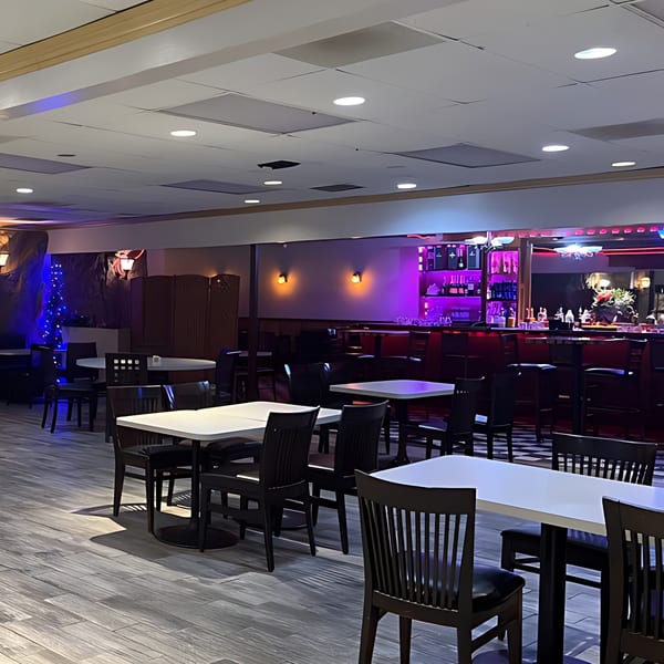 LE Chef Mediterranean restaurant interior with dining tables, chairs, and a bar with purple lighting.
