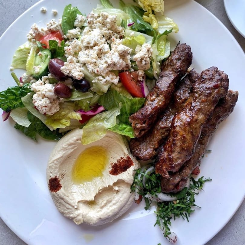LE Chef Mediterranean plate with grilled meat skewers, hummus, and a fresh salad with feta.