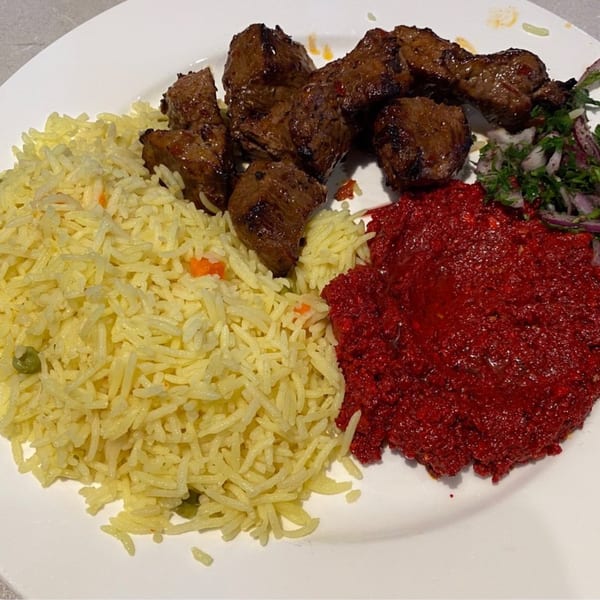 LE Chef Mediterranean's plate with grilled meat, yellow rice, red sauce, and a side salad.